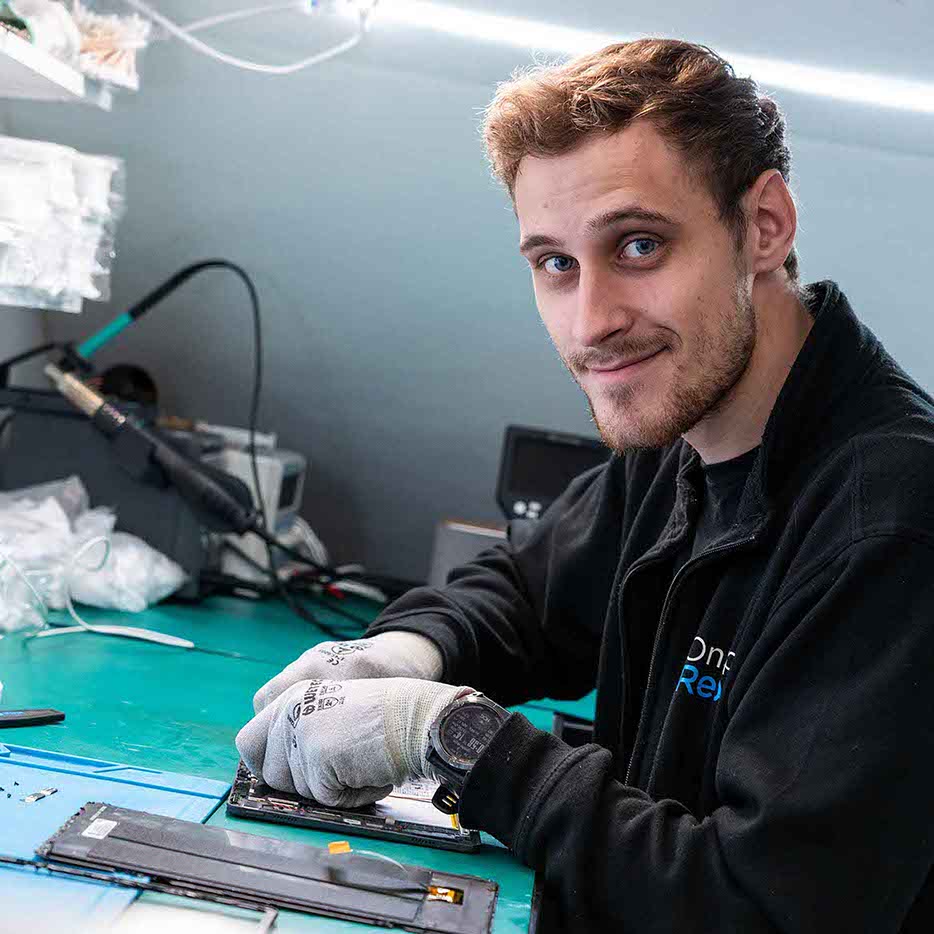Medarbejder smiler i mens han reparerer defekt mobil. 